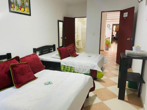 a room with three beds with red pillows at Hotel Colonial El Bosque A in Tunja