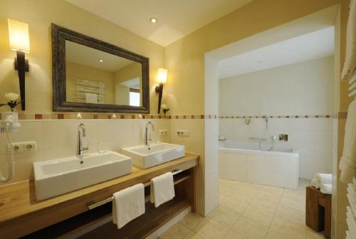 a bathroom with two sinks and a mirror and a tub at Staudacherhof in Garmisch-Partenkirchen I Blick aufs Zugspitzmassiv I einzigartige Bayurvida Küche in Garmisch-Partenkirchen