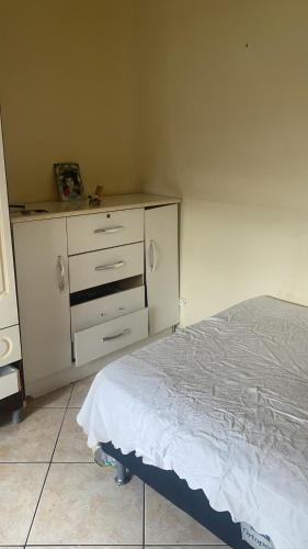 a bedroom with a white bed and a dresser at Condomínio azul in Paraty