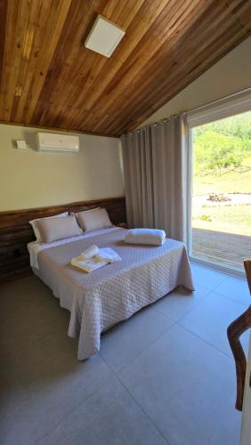 a bedroom with a bed and a large window at CASA GRÊS - Pousada Vale das Escarpas in Timbe do Sul