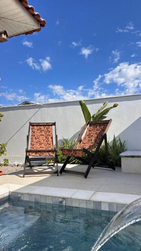 two chairs sitting next to a swimming pool at A Casinha de Madeira in Balneário Gaivotas