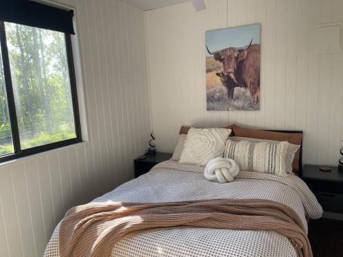 a bedroom with a bed with a bull picture on the wall at Hayden's Place in Wamuran