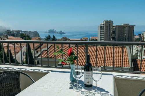 a table with a bottle of wine and two glasses at Apartments Nada in Petrovac na Moru