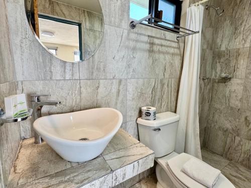 a bathroom with a sink and a toilet and a mirror at Charly Beach Hotel in Isla Mujeres