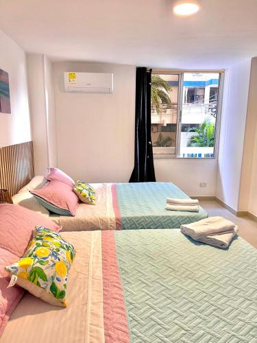 two beds in a room with a window at IvoMar Karey 102 in Rodadero