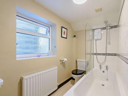 a bathroom with a tub and a toilet and a window at 2 Bed in Matlock oc-81116 in Crich
