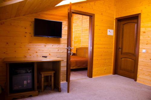 a living room with a television and a room with a bed at Arnika Hotel in Bukovel