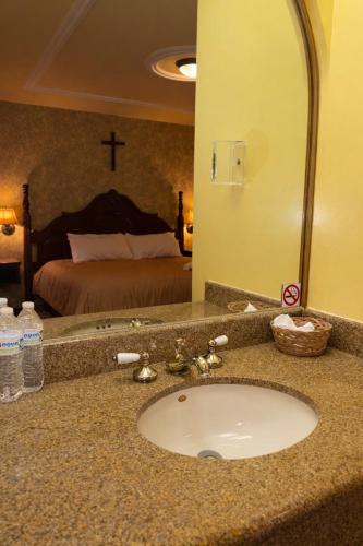 ein Badezimmerwaschtisch mit Waschbecken vor einem Schlafzimmer in der Unterkunft Hotel Fiesta Brava Inn Río Bravo in Primero de Mayo