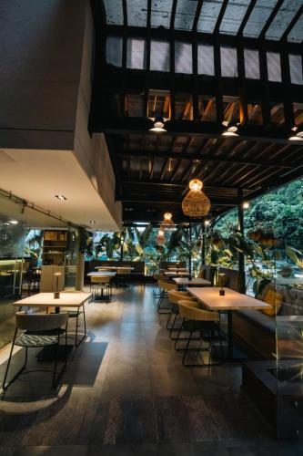 a dining room with tables and chairs and trees at Ambar Hotel Boutique Cali in Cali