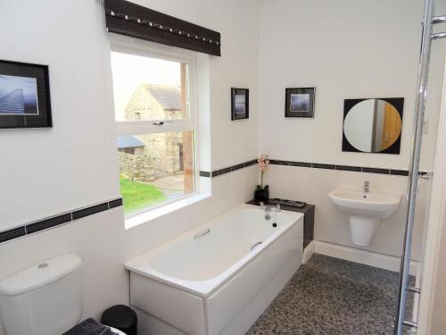 a white bathroom with a tub and a sink at Sharp Edge in Penrith