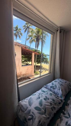 a bedroom with a window looking out at the beach at Suítes Recanto dos papagaios in Angra dos Reis
