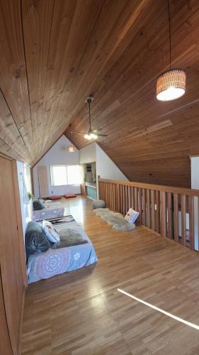 a room with two beds and a wooden ceiling at Cabin Dilusso in Hokuto