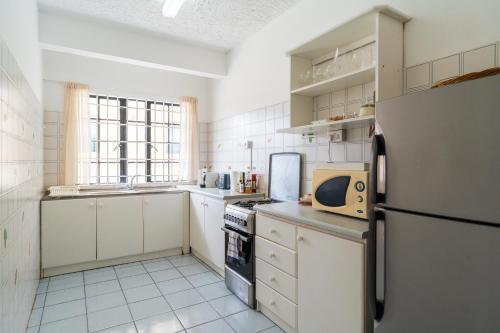 a kitchen with white cabinets and a refrigerator at Mont Choisy Lodge 7 Rooms, Large Pool, 2 Min Walk to Beach in Grand-Baie