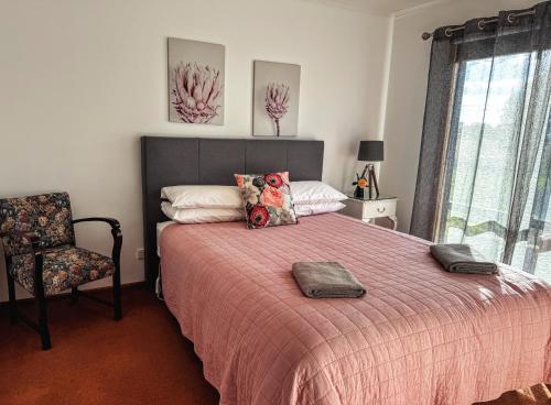 a bedroom with a bed with a red blanket and a chair at Bonnie Views Cottage in Clunes