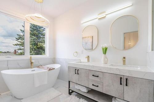 a white bathroom with a tub and a large mirror at Toronto Midtown Luxury Living in Toronto