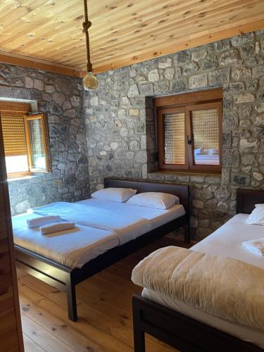 two beds in a room with a stone wall at Moonlight House in Vusanje
