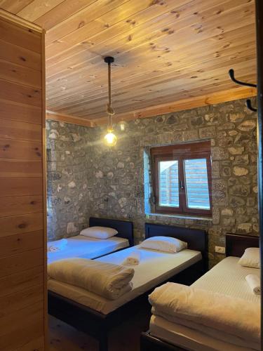 two beds in a room with a stone wall at Moonlight House in Vusanje
