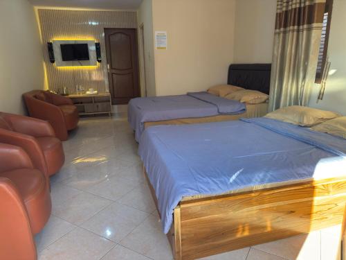 a bedroom with two beds and a chair and a television at Homestay Lereng Bromo in Bromo