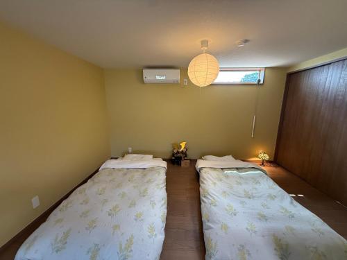 two twin beds in a room with a window at Private house 海Kai in Nagato