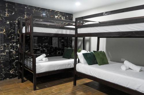 a bedroom with two bunk beds with white sheets at Brisas del Mar, Costa Azul - Private Pool in Acajutla