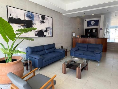 a living room with blue couches and a potted plant at Hotel Atilana in Guadalajara