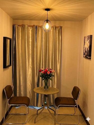 a table with a vase of flowers and two chairs at Pongsakorn Boutique Resort in Lat Krabang