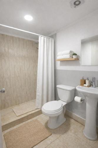 a white bathroom with a toilet and a sink at Puna Hostel in San Pedro de Atacama