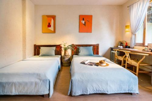 two beds in a room with a desk and a sink at Về Homestay Ninh Bình in Ninh Binh