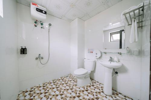 a white bathroom with a toilet and a sink at Cat Ba Flora Hotel in Cat Ba