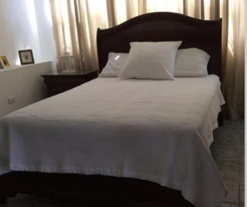 a large white bed with white sheets and pillows at Tropical to go! Apt 1 in Fajardo