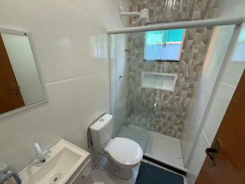 a white bathroom with a toilet and a sink at Mar Azul Beach House in Cabo Frio