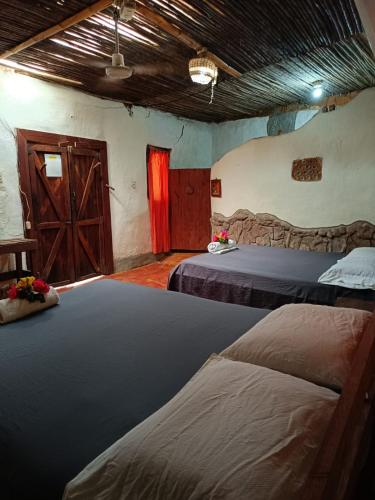 a room with two beds and a wooden door at Cabañas Ecológicas in Tela in Tela