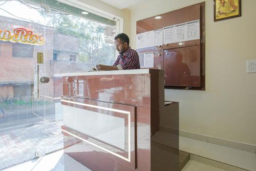 a man sitting at a counter in a kitchen at Hotel O Sunrise in Ludhiana