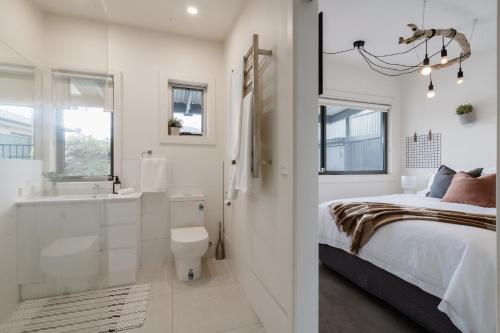 a white bedroom with a bed and a bathroom at Salty Breeze on Graeme in Dromana