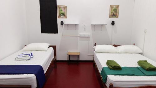 two beds in a room with white walls at Zeenath Villa - Arugambay in Arugam Bay