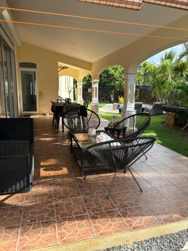 an outdoor patio with chairs and a table at Studio tout confort avec piscine pour les amoureux des toutous in Roches Noires