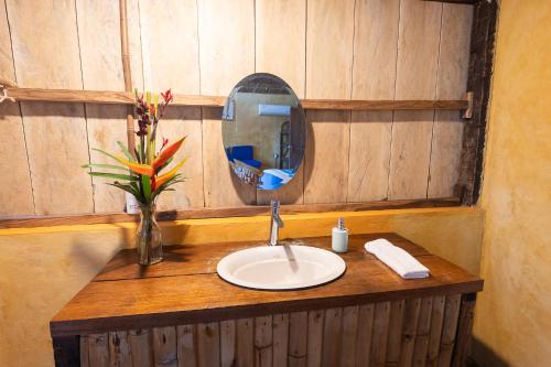 a bathroom sink with a mirror and a vase with flowers at Los Amigos Ecoturismo y Reserva Natural in Catemaco
