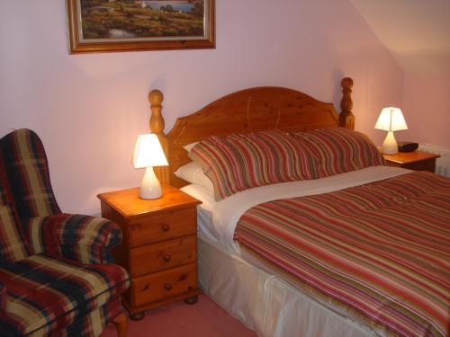 a bedroom with a bed and a chair and two lamps at Rosmo House B&B in Westport