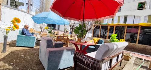 a man sitting in a chair under a red umbrella at T-Suru Hotel & Cafe Leh in Leh