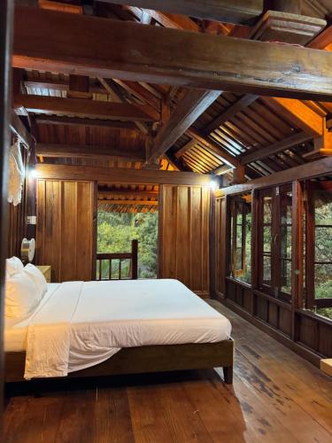 a bedroom with a bed in a room with wooden walls at Núi Dinh Stilt House - Phú Mỹ in Ấp Long Cát