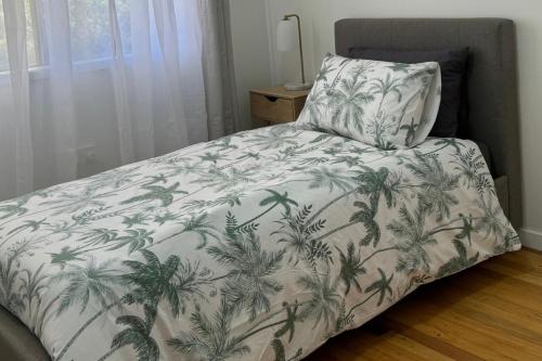 a bed with a white blanket with palm trees on it at Healy Retreat in Mary Kathleen