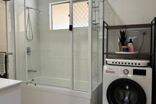 a bathroom with a shower and a washing machine at Healy Retreat in Mary Kathleen