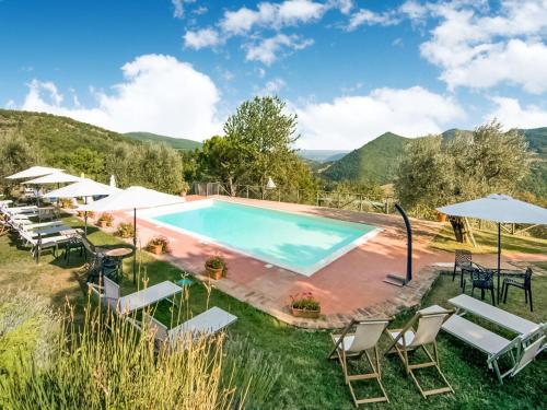a pool with chairs and umbrellas on a hill with mountains at Farmhouse in Monte Santa Maria Tiberina with garden in Monte Santa Maria Tiberina