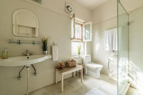 a white bathroom with a sink and a toilet at Barwara Kothi in Jaipur