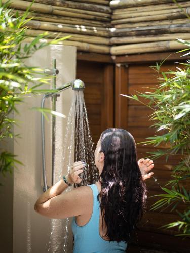 a woman standing in a shower with water at Mokusiga Villas in Tangangge