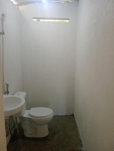 a bathroom with a white toilet and a sink at Kalma Kubo Siargao in San Isidro