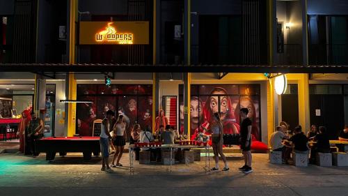 a group of people standing outside of a store at night at Whoopers Hostel Ao Nang - By The Beach in Ban Khlong Haeng