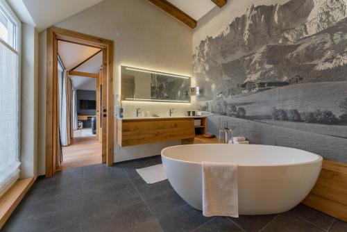a bath tub in a bathroom with a wall mural at AlpenParks Hotel Maria Alm in Maria Alm am Steinernen Meer