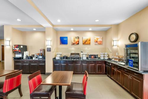 a restaurant with a table and chairs and a kitchen at Comfort Suites Orlando Airport in Orlando