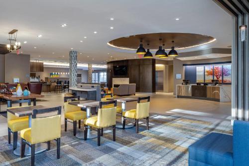 a hotel lobby with tables and yellow chairs at Cambria Hotel Manchester South Windsor in South Windsor